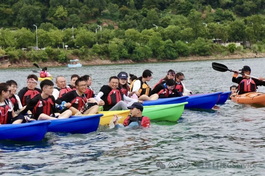 同事们身穿红色救生衣分乘皮划艇并排前行，互相泼水嬉闹